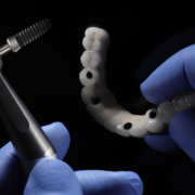a full arch of teeth with a tool to place it onto the mouth