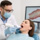 Image of a dentist examining a patient's jaw with a 3D scanner, illustrating the assessment process for full mouth dental implants.