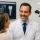 A friendly dental implantologist in West Palm Beach, FL smiling and consulting with a patient, showcasing modern dental technology in the background. No text on image.