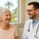 A smiling senior woman is talking to a male dentist in his office in West Palm Beach, Florida. No text on image.