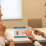 Patient consults with dentist about single tooth implant and dental bridge options.